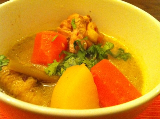 A bowl of cà ri gà with chicken, carrots, potato, and cilantro.